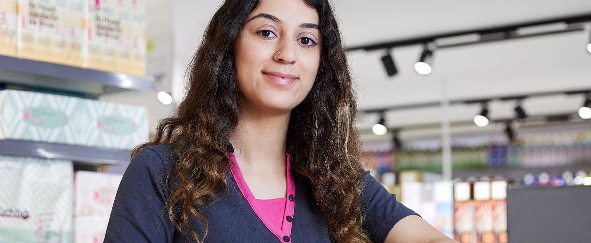 Eine Mitarbeiterin steht vor einem Regal.