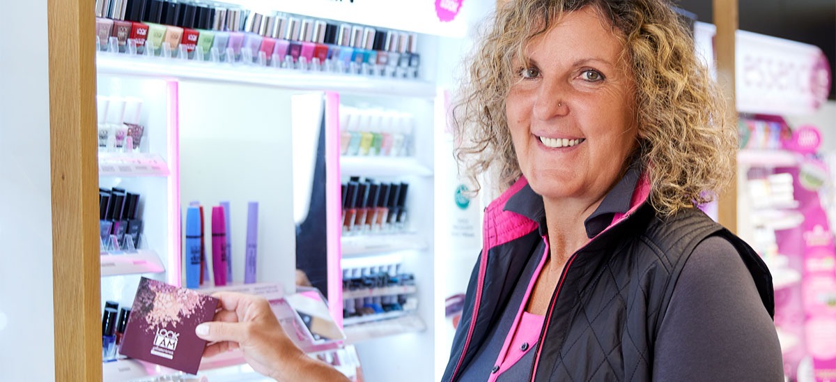 Eine lächelnde Mitarbeiterin zeigt eine Lidschattenpalette.