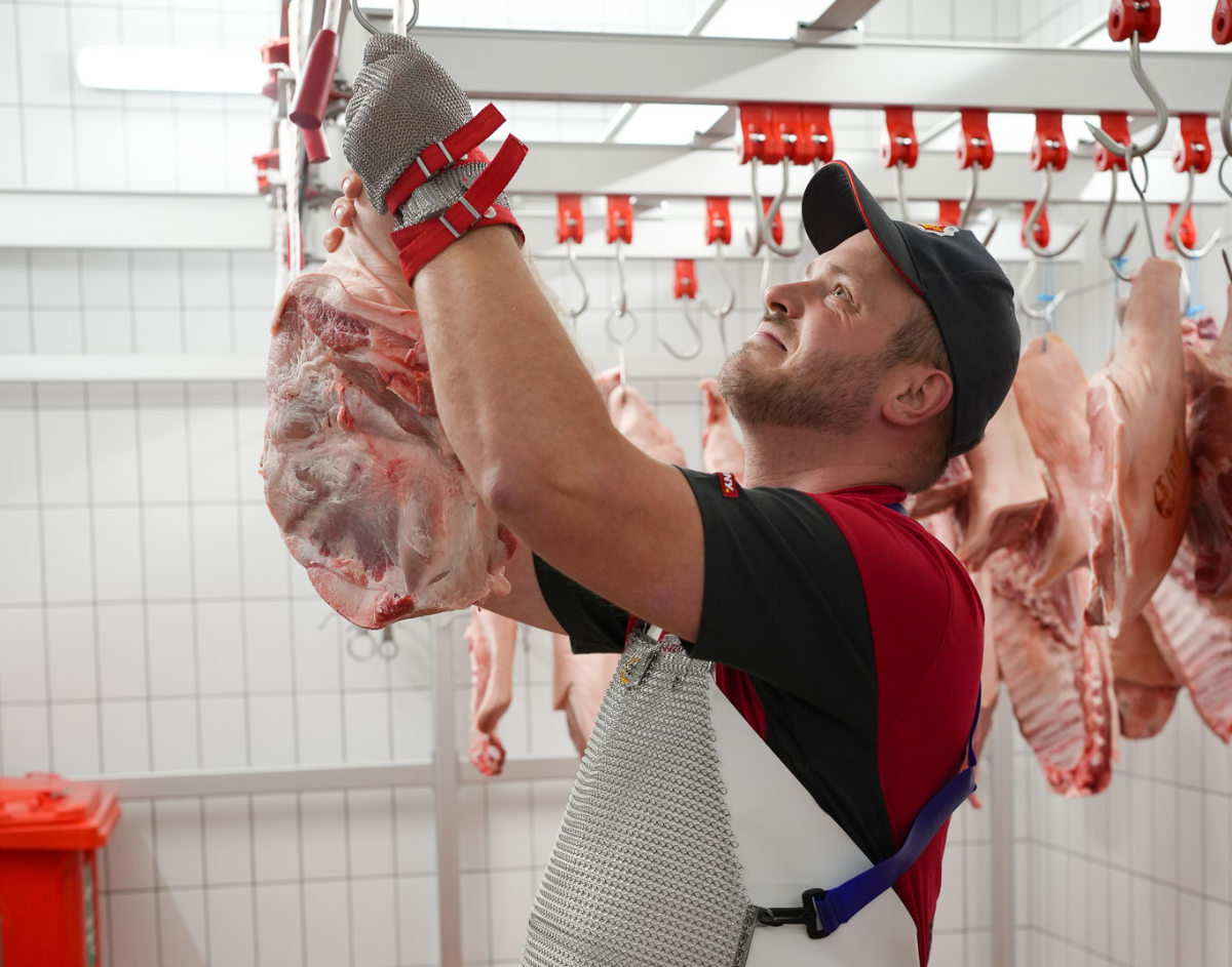 Ein Mitarbeiter hängt Fleisch auf.