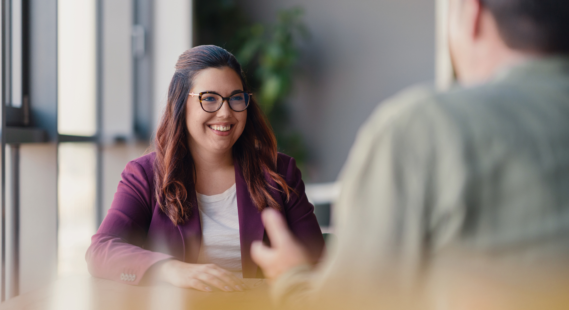 Eine lächelnde Frau sitzt an einem Tisch.