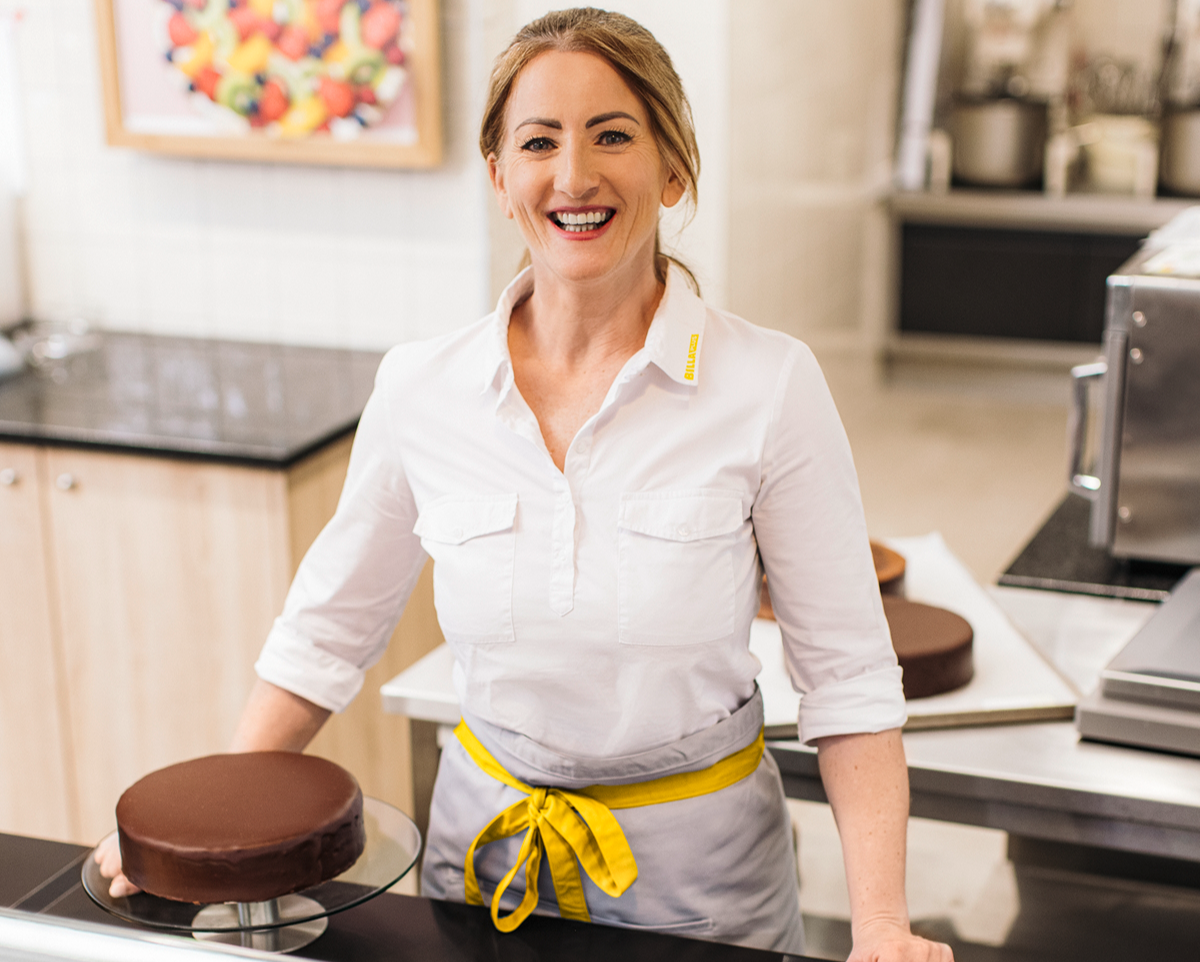 A smiling employee in front of a cake. 