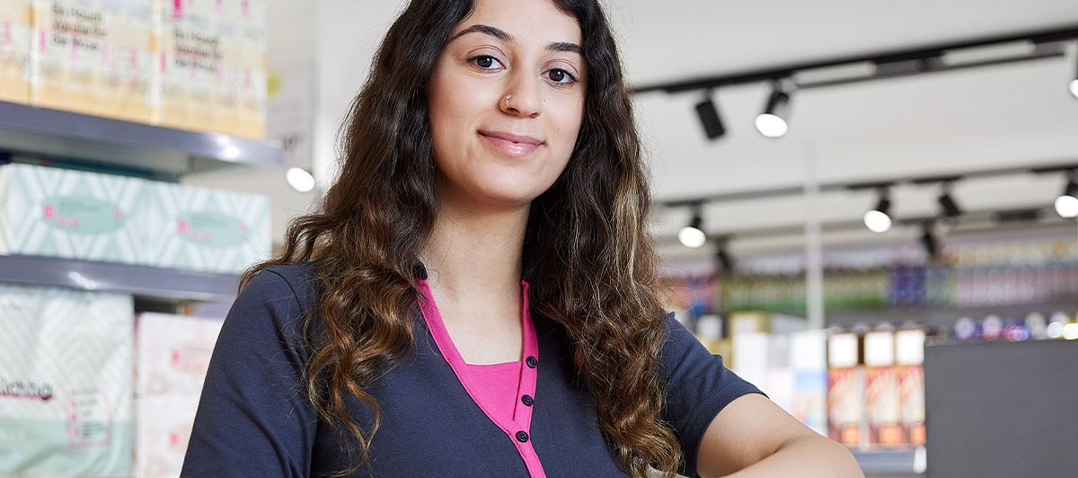 A smiling employee in front of a shelf.