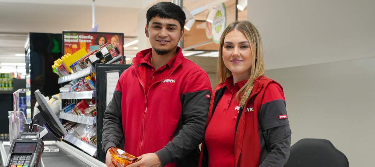 Two smiling employees in front of the check out. 