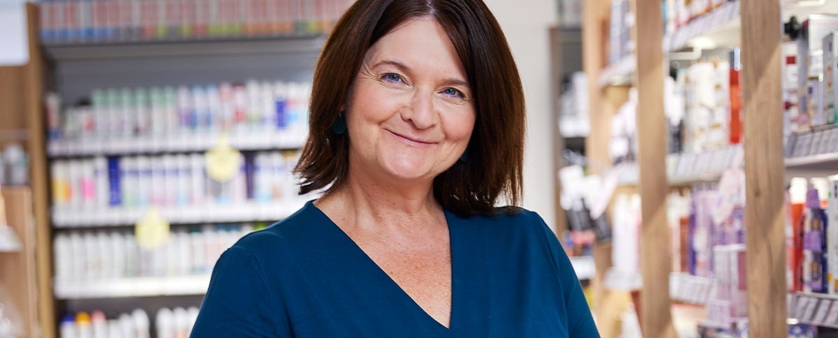 A smiling employee in front of a shelf.